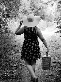 Full length of woman wearing hat standing on field with picnic