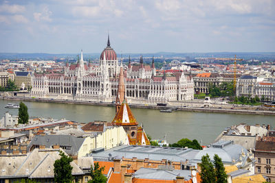 Aerial view of buildings in city against cloudy sky