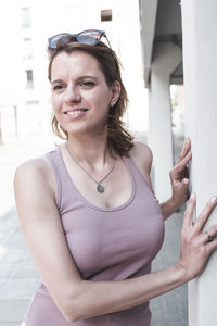 Portrait of young woman standing against building