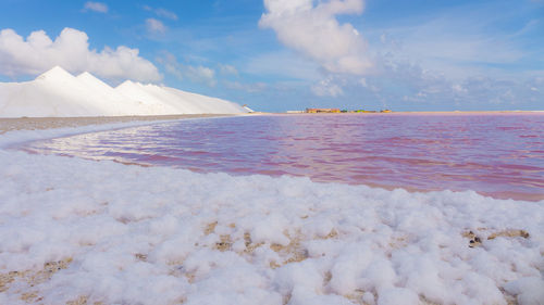 Salt flat by sea against sky