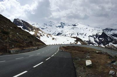 Road by snowcapped mountains against sky