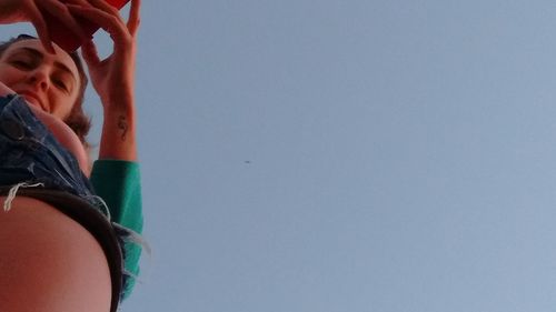 Low section of woman standing against clear blue sky