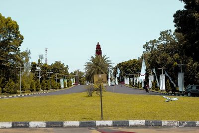 Road by trees in city against clear sky