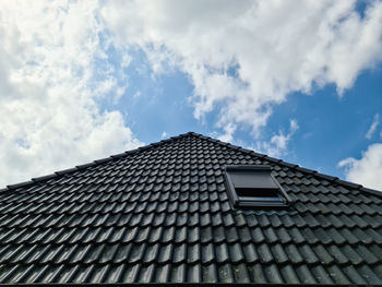 Open roof window in velux style with surrounding black roof tiles