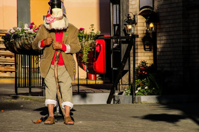 Full length of man face covered with fabric standing on street during sunny day