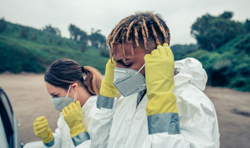 Close-up of man and woman wearing mask standing outdoors