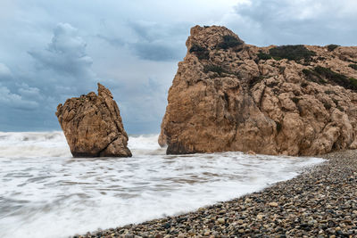 Rock formation on beach against sky