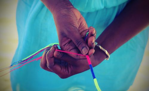 Midsection of woman making decoration with string 