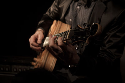 Midsection of man playing guitar