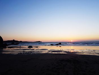 Scenic view of beach against clear sky during sunset