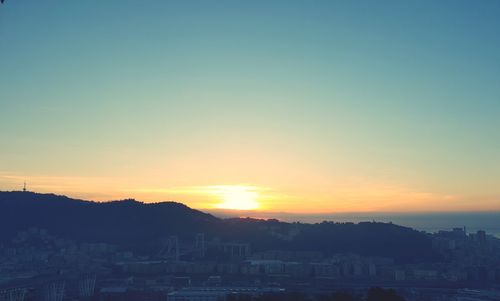 Silhouette buildings against clear sky at sunset