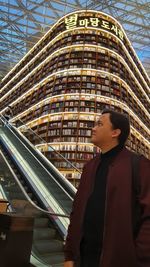 Side view portrait of young man standing against built structure