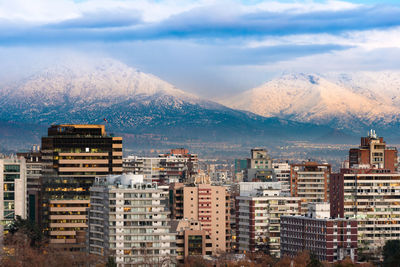 Buildings in city against mountains during winter