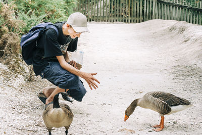 Full length of man by geese on field