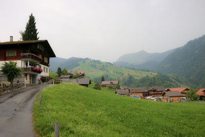 Houses on field by buildings against sky