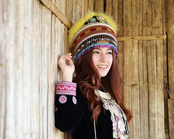 Portrait of smiling young woman standing against wall