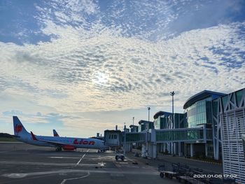 Airplane on airport runway against sky during sunset