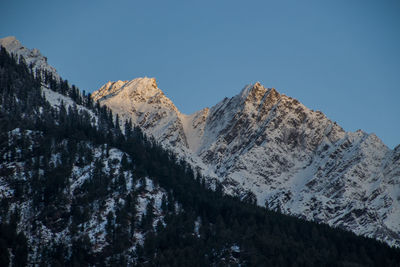 Low angle view of snowcapped mountains against clear sky