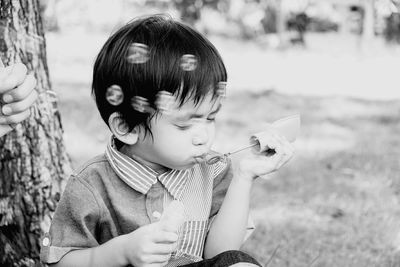 Boy blowing bubbles on field