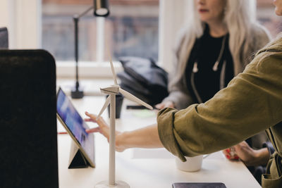 Business colleagues discussing over wind power on digital tablet at office desk