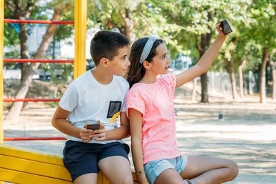 Rear view of friends sitting on mobile phone