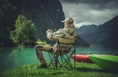 Mature man sitting on chair with fishing rod