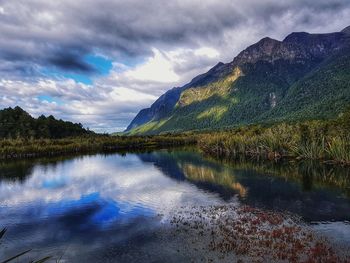 Scenic view of lake by mountains against sky