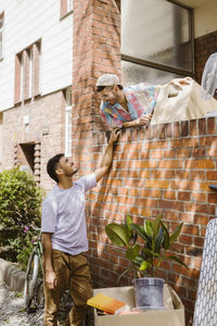 Man talking to boyfriend leaning on brick wall during relocation of house