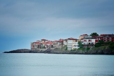 Houses by sea against sky