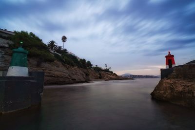 Lighthouse amidst sea and buildings against sky