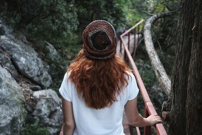 Rear view of woman standing against trees in forest