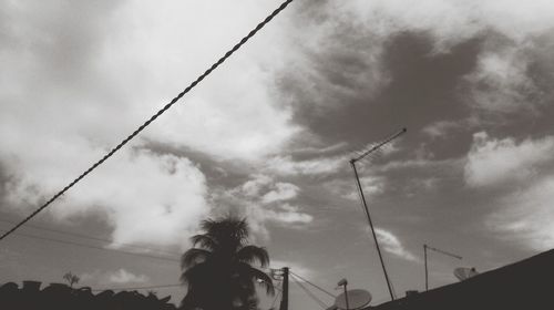 Low angle view of power lines against cloudy sky