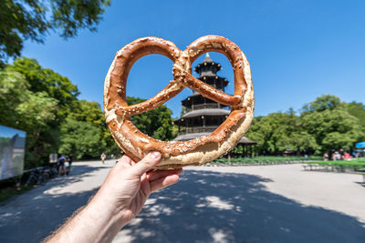 Close-up of hand holding bread against sky