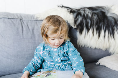 Cute girl sitting on sofa at home