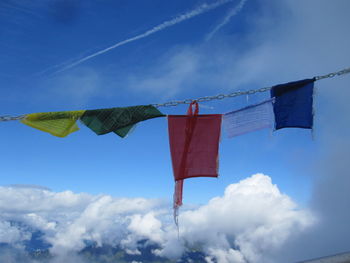 Low angle view of prayer flags hanging from chain against sky