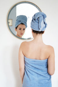 Reflection of woman on mirror in bathroom at home