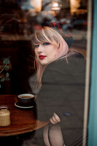 Young woman sitting by coffee cup on table