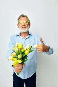 Portrait of woman holding flowers against white background