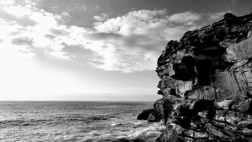 Rock formation on beach against sky