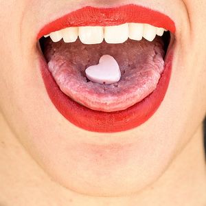Close-up of heart shape candy on woman mouth