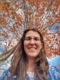 Portrait of smiling young woman against trees