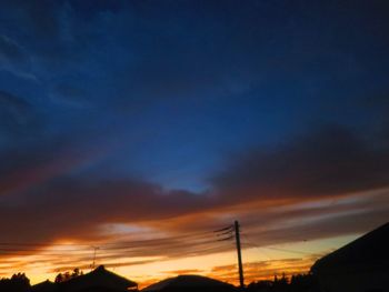 Low angle view of silhouette electricity pylon against sky during sunset