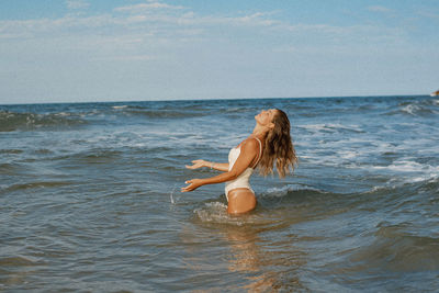 Rear view of woman in sea against sky