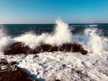 Waves splashing in sea against sky