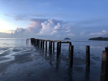 Wooden posts in sea against sky