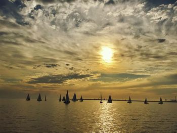 Silhouette boats sailing in sea against sky during sunset