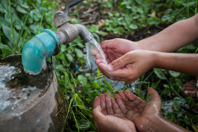 Cropped hands of children at drinking fountain