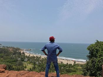 Rear view of man standing at beach against clear sky