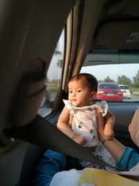 Cute baby girl looking through window in car