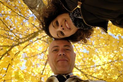 Low angle portrait of family standing against trees during autumn